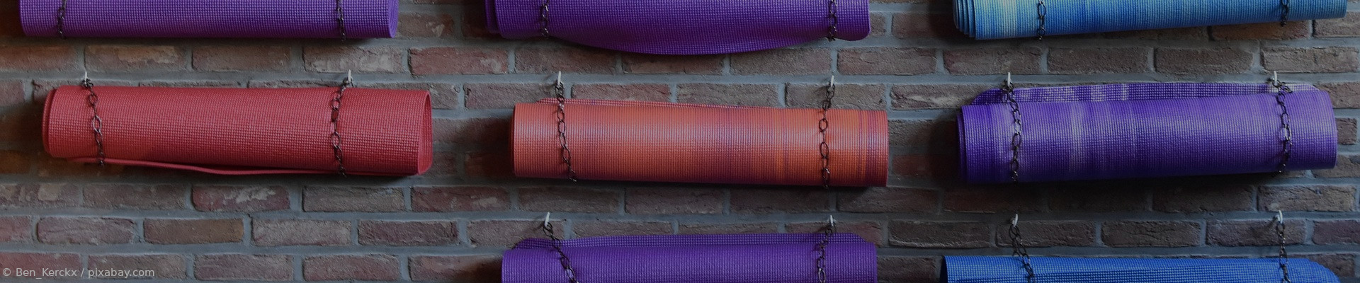 Viele Yogamatten an einer Wand